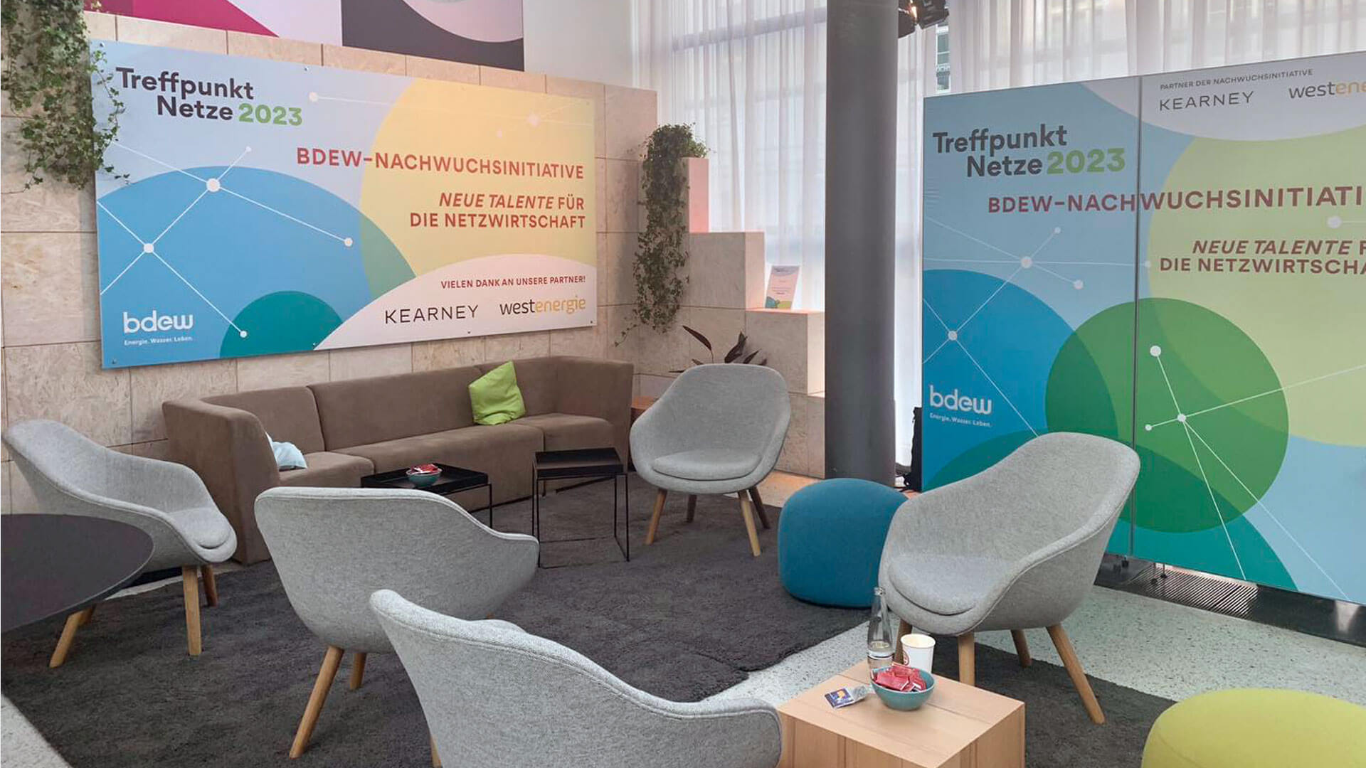 Loungebereich beim Treffpunkt Netze 2023 mit großflächigem Event Branding und Key Visual des BDEW-Kongresses.