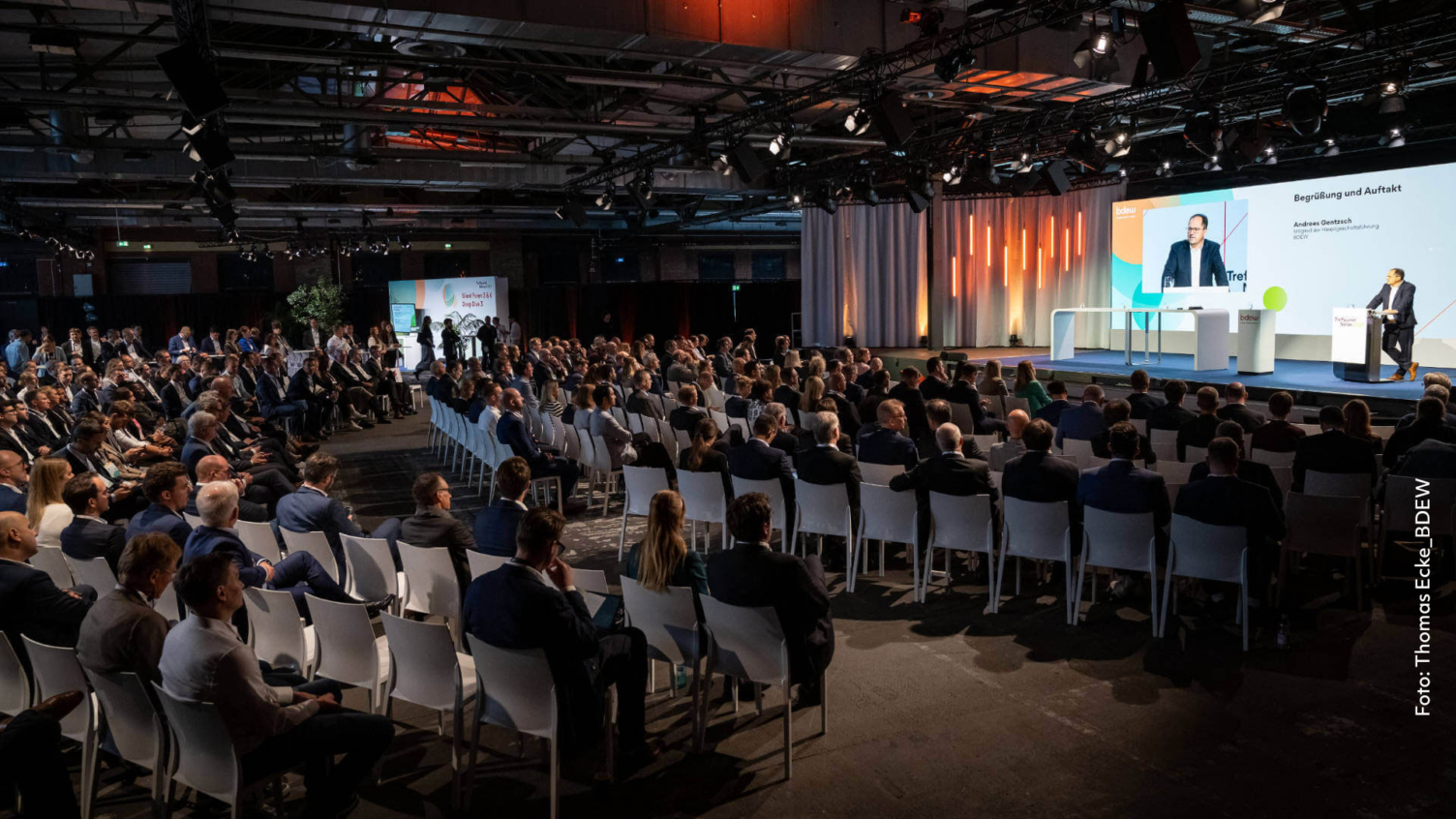 Plenarsaal beim Treffpunkt Netze 2025 mit Bühne, Speaker und großflächigem Event Branding auf der Leinwand.