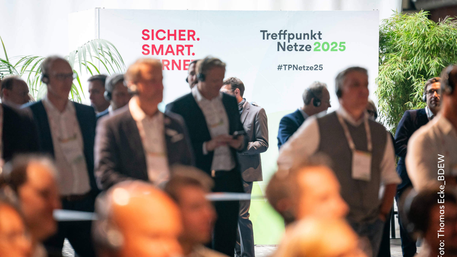 Teilnehmende beim Treffpunkt Netze 2025 vor einer Branding-Wand mit Key Visual und Hashtag #TPNetze25.